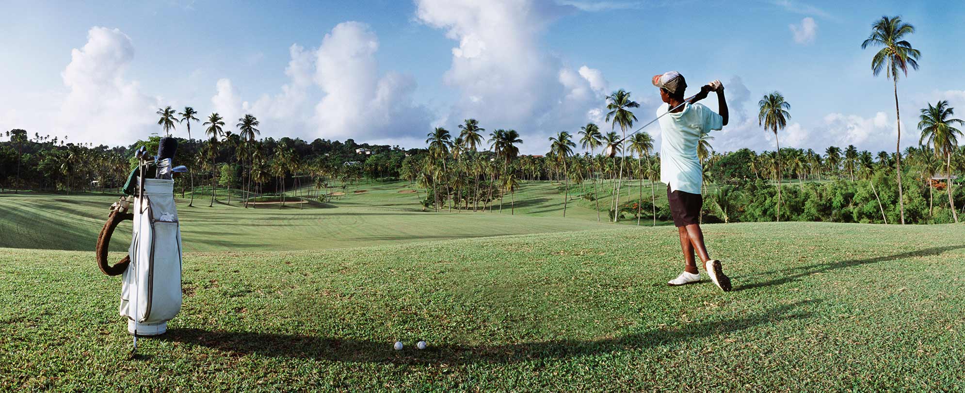 A golfer on a course is in a backswing position. 